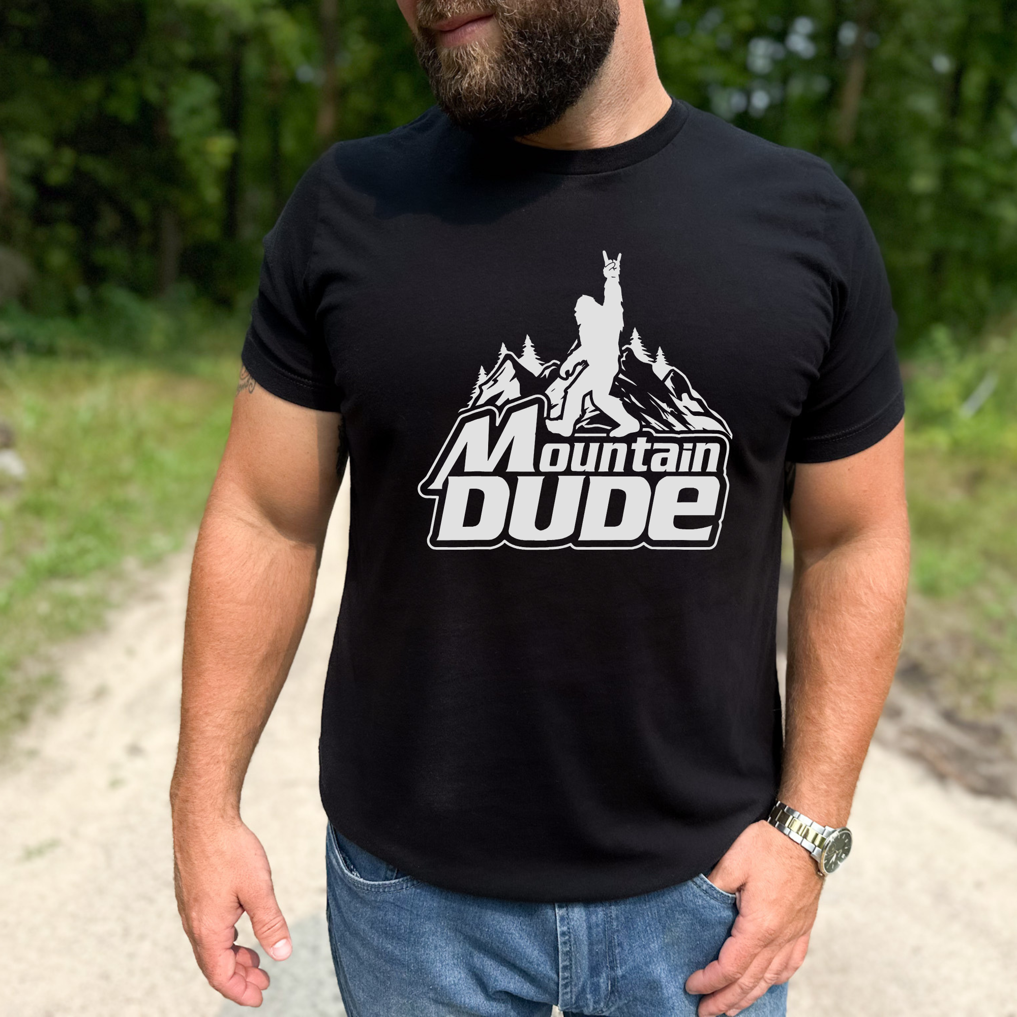 Person wearing a black t-shirt with 'Mountain Dude' graphic outdoors.
